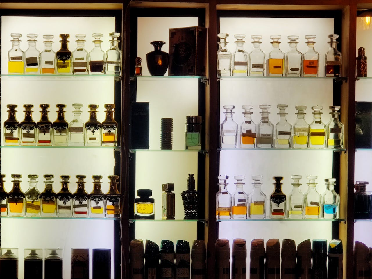 our-experience Aesthetic arrangement of diverse perfume bottles on illuminated shelves showcasing luxury fragrances.